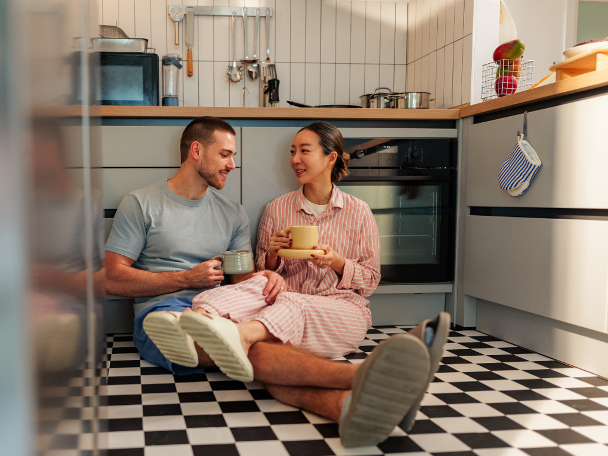a man and woman sitting on the floor with cups of coffee